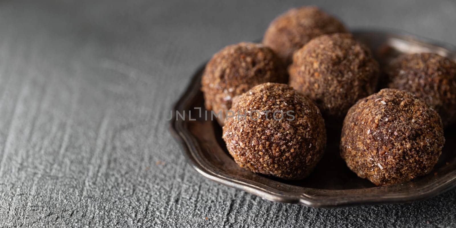 Decorating of artisan chocolate truffle candies with berry and fruit filling on dark background from confectionary. Handmade or handcrafted bonbons, chocolatier concept. Horizontal banner, copy space