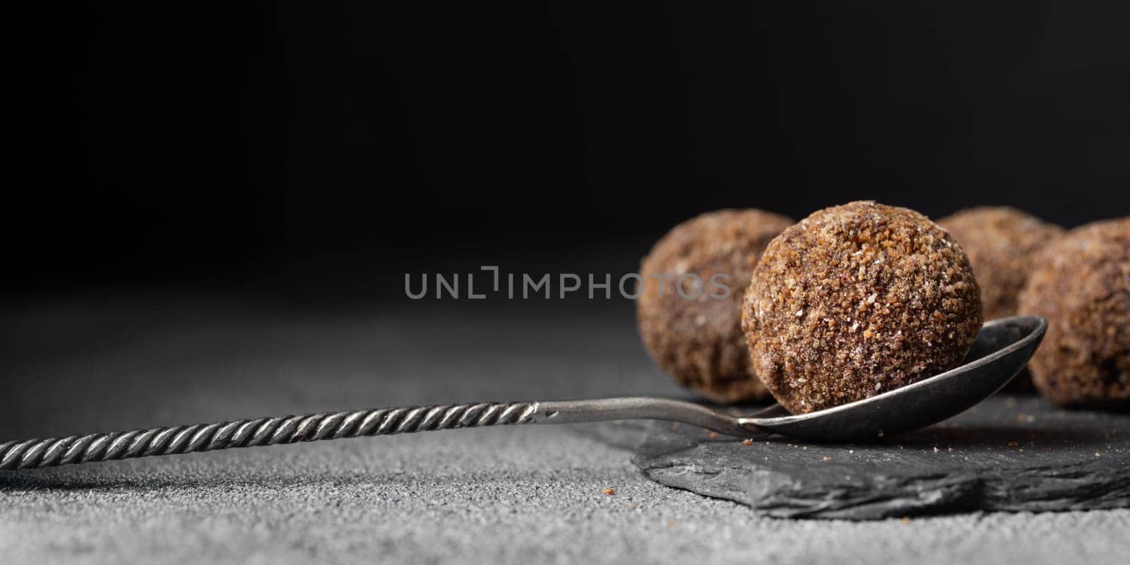 Decorating of artisan chocolate truffle candies with berry and fruit filling on dark background from confectionary. Handmade or handcrafted bonbons, chocolatier concept. Horizontal banner, copy space