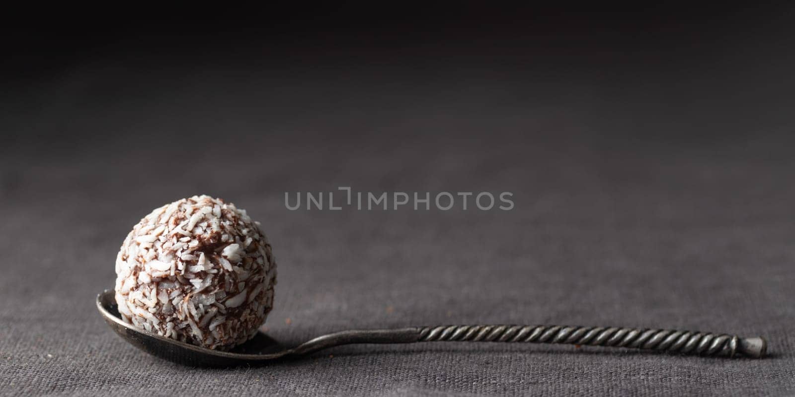 Artisan chocolate coconut truffle candies on dark background from confectionary. Handmade or handcrafted bonbons, chocolatier concept. Horizontal banner, copy space