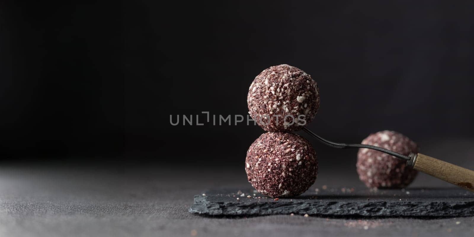 Artisan chocolate truffle candies with berry and fruit filling on dark marble background from confectionary. Handmade or handcrafted bonbons, chocolatier concept. Horizontal banner, copy space