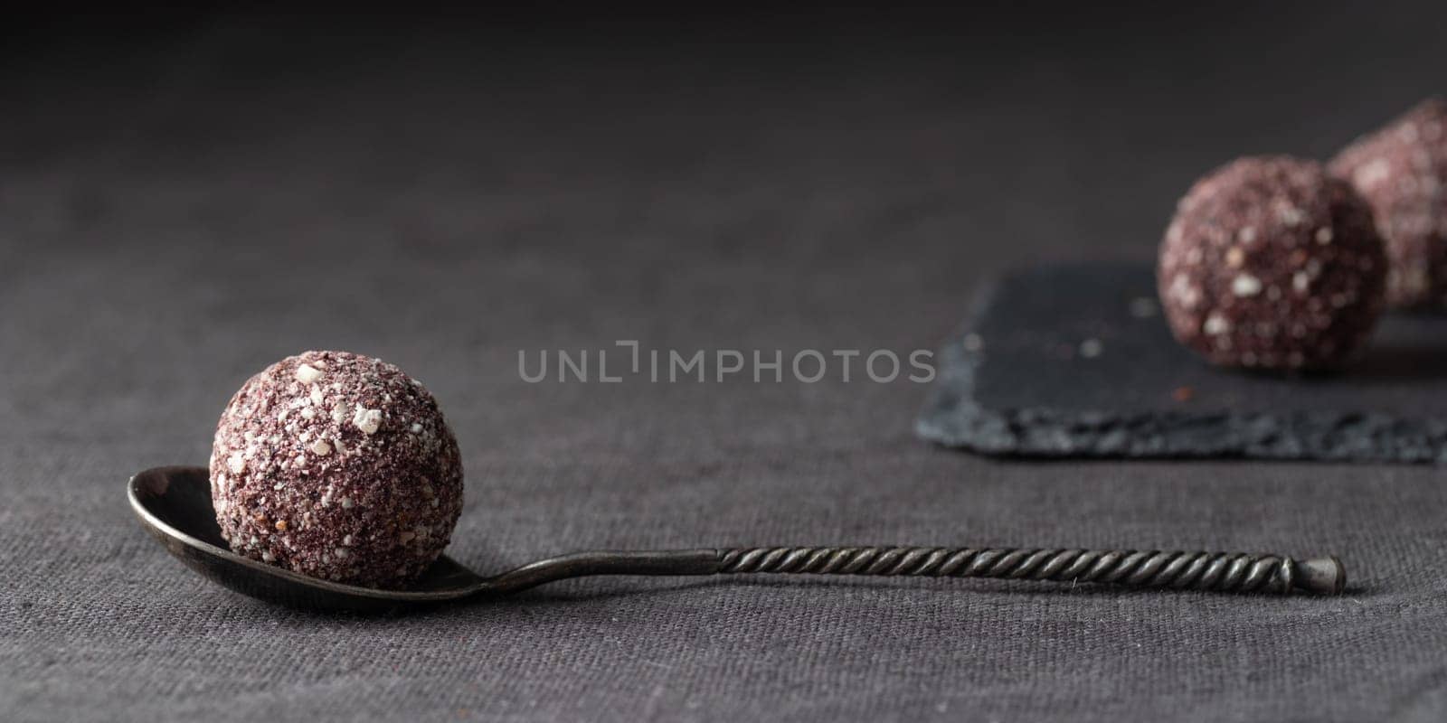 Artisan chocolate truffle candies with berry and fruit filling on dark marble background from confectionary. Handmade or handcrafted bonbons, chocolatier concept. Horizontal banner, copy space