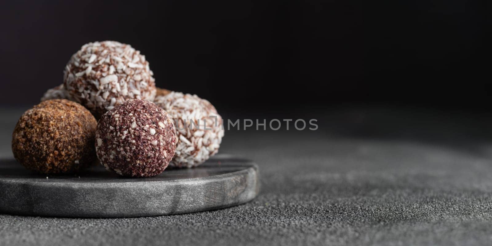 Assortment of gourmet handcrafted vegan chocolate truffle candies on dark marble background from premium confectionary. Handmade bonbons chocolatier concept. Horizontal banner with copy space