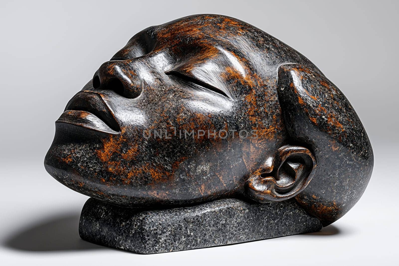 A beautifully carved stone sculpture captures the serenity of a woman's face, highlighting her calm expression and exquisite details in the stone surface.