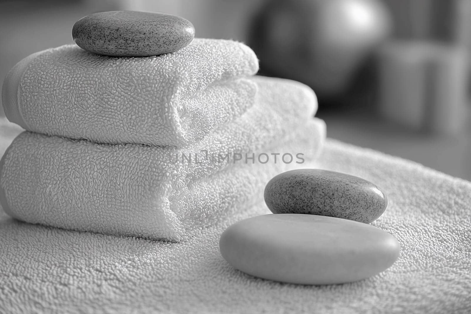 Stacked towels lie neatly beside pebbles in a serene spa environment, designed for relaxation and tranquility after treatments.