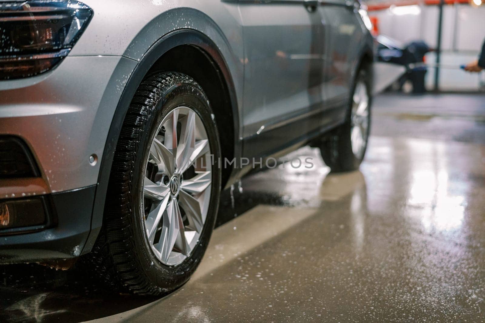 Soap spray drips from car doors and wheels onto the car wash floor. High quality photo