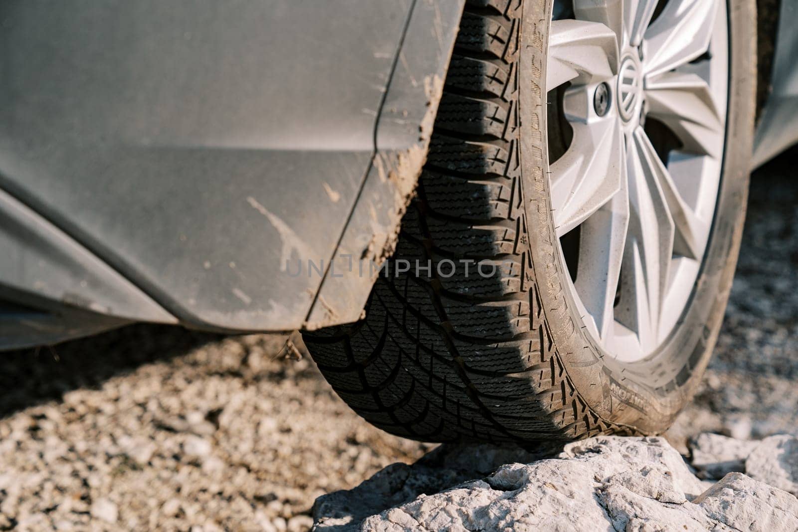 Car stands with a wheel on a rocky ledge with sagging. Close-up. High quality photo