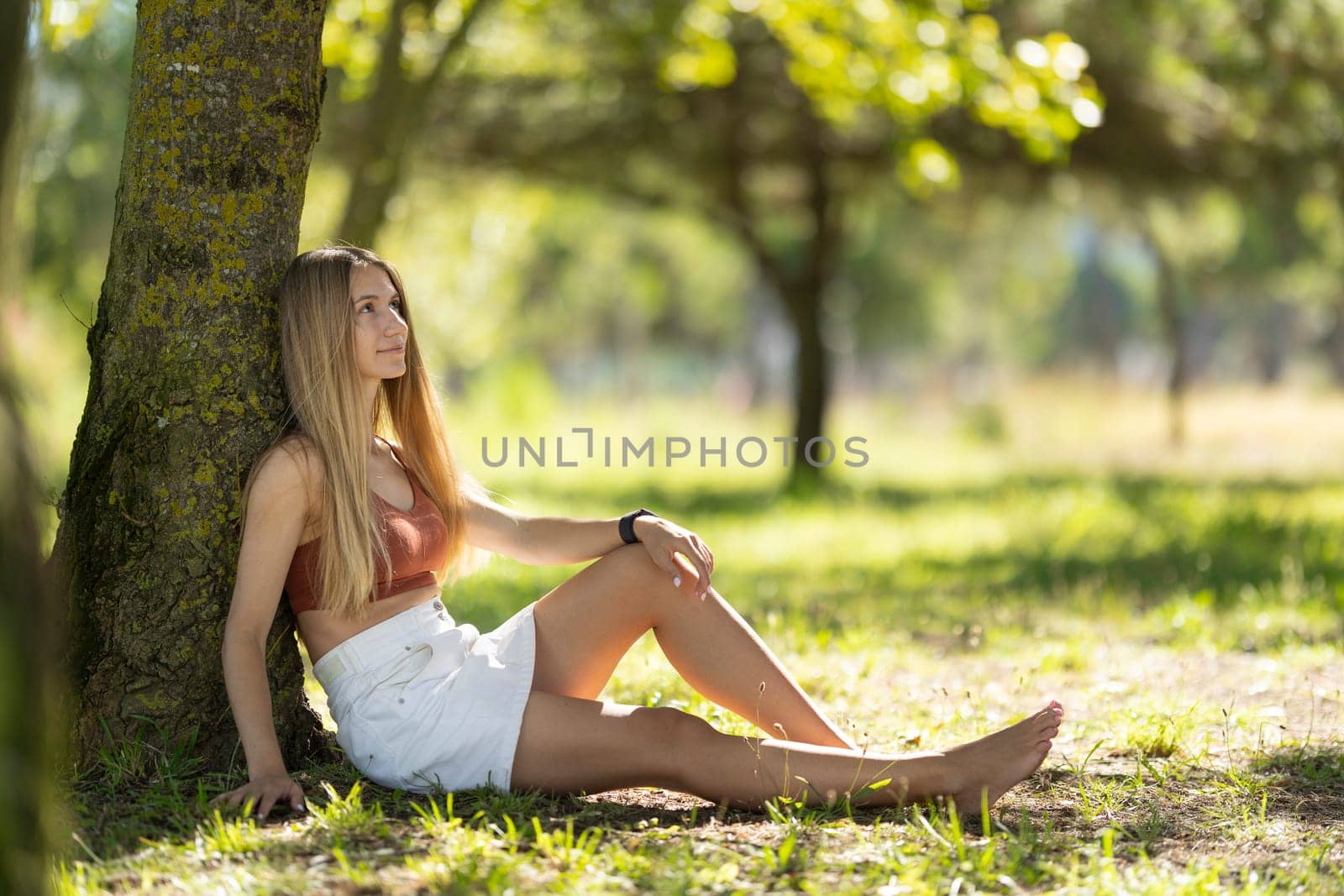 Young woman is enjoying the peace and quiet of nature while sitting in the grass