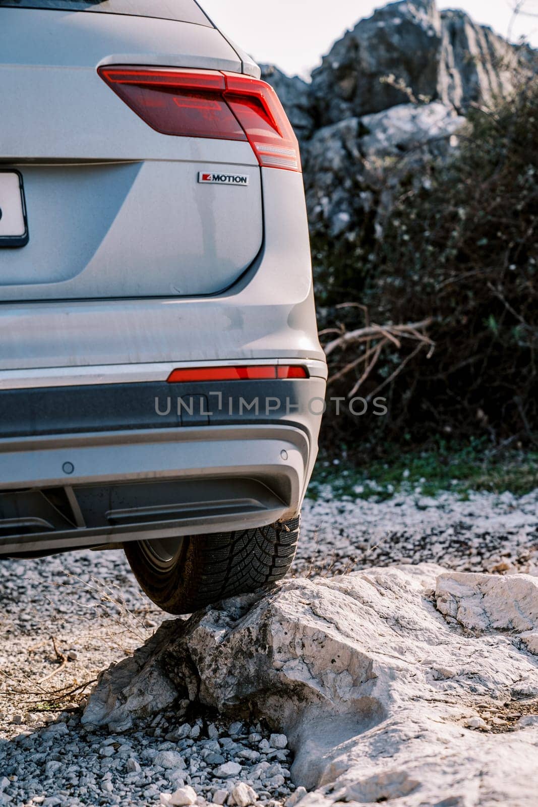 Car stands with its rear wheel on a stone on the road. Back view. High quality photo