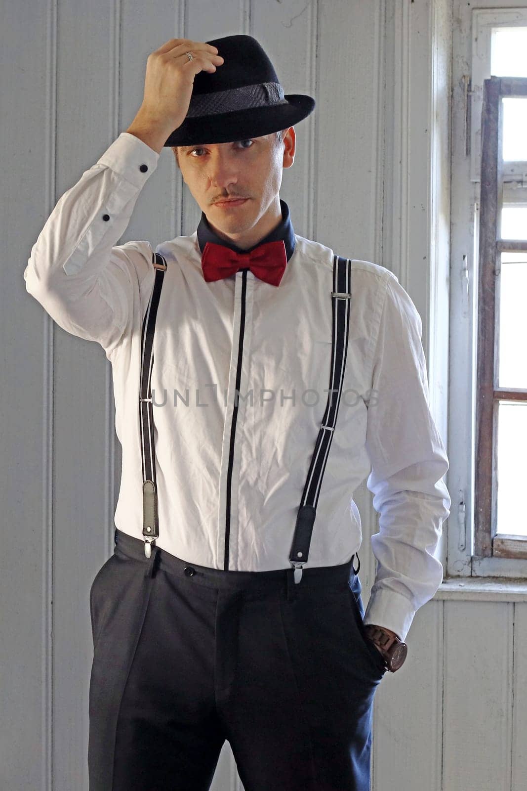 A man in 20s retro style with shirt, suspenders and hat