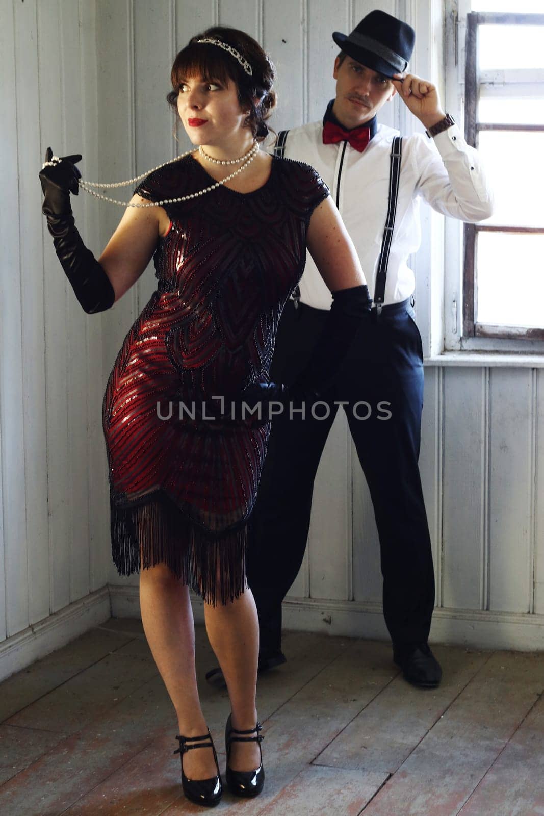 A couple in 20s retro style dancing in front of a window