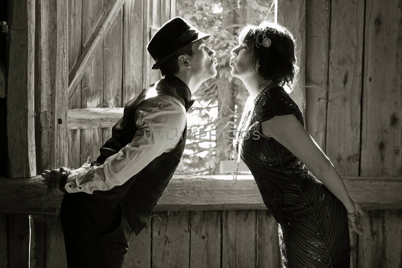 A pair of lovers in 20s retro style kissing in front of a window