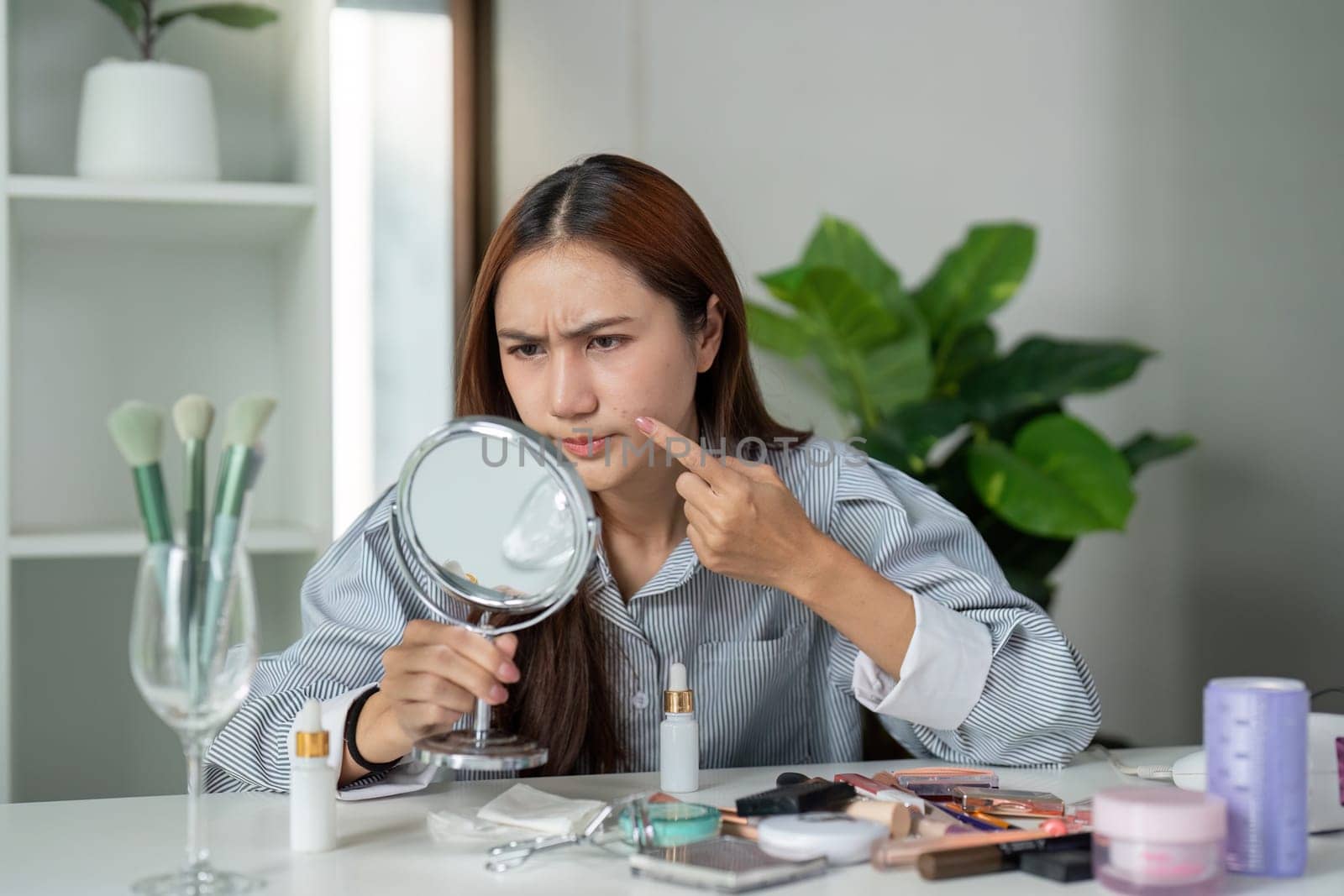 A woman closely inspects her skin in the mirror, reflecting the challenges of skincare while demonstrating a commitment to personal care.