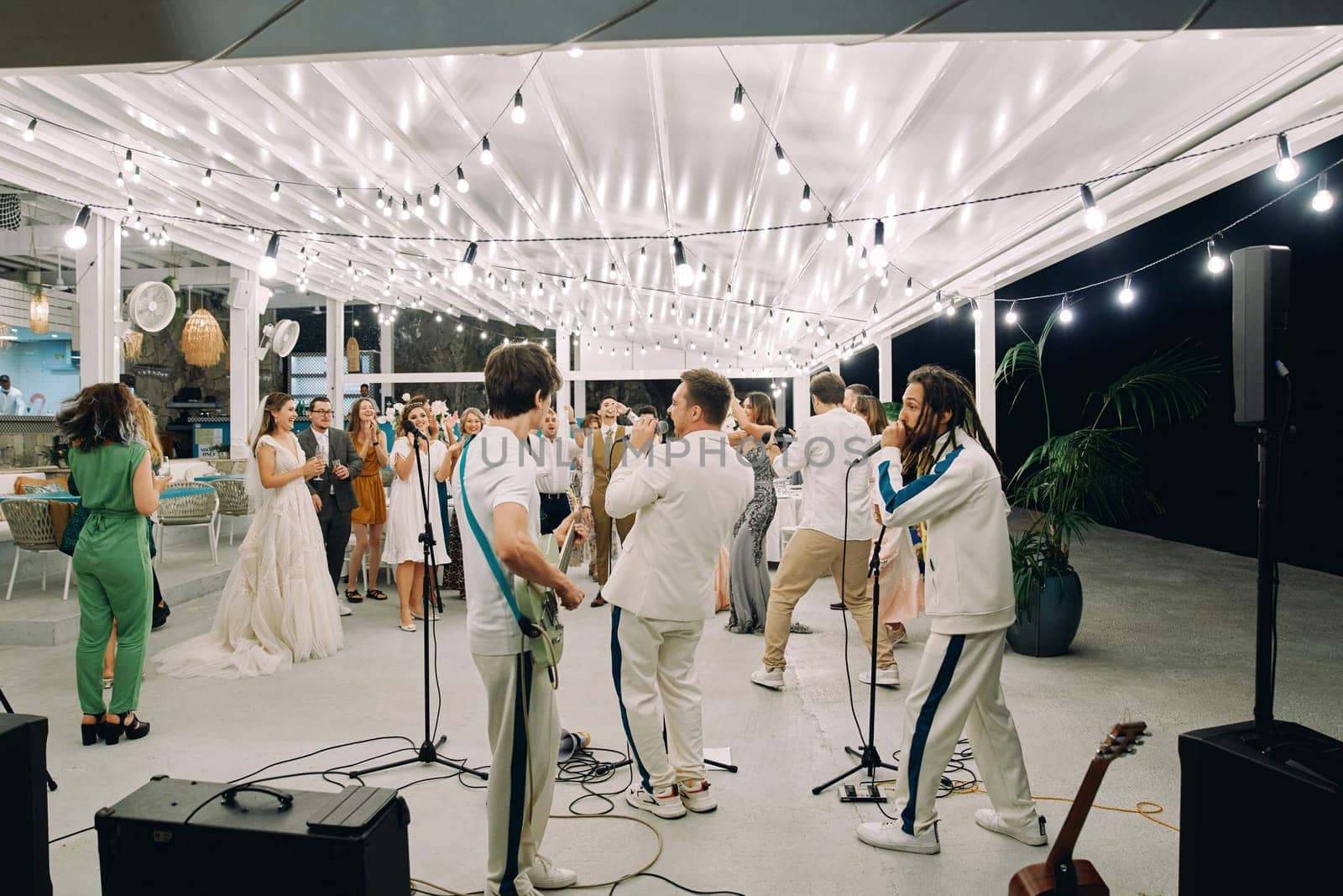 Guests applaud a performing musical group on a terrace by the sea. High quality photo