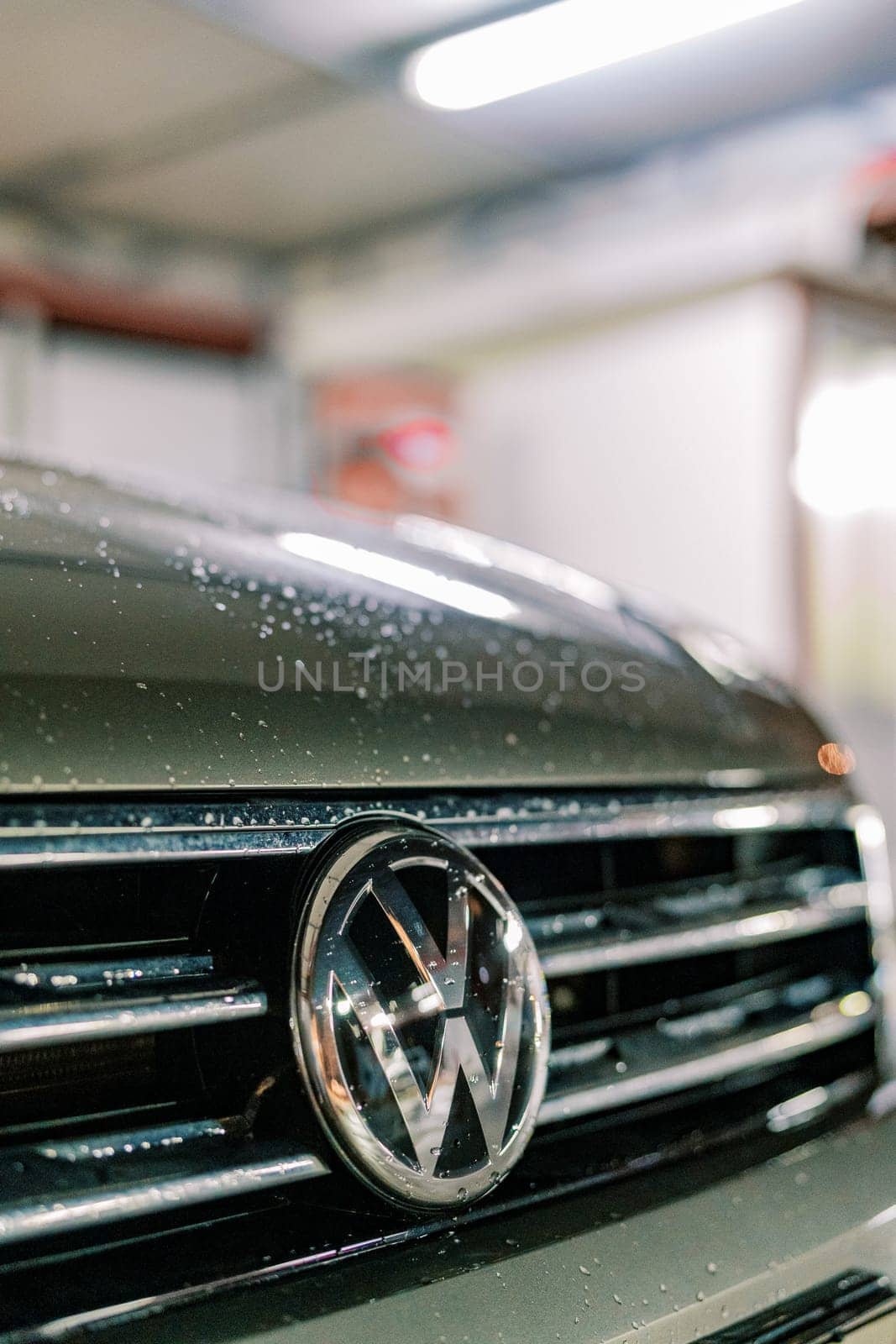 Wet hood of a car with a Volkswagen sign. Cropped. High quality photo
