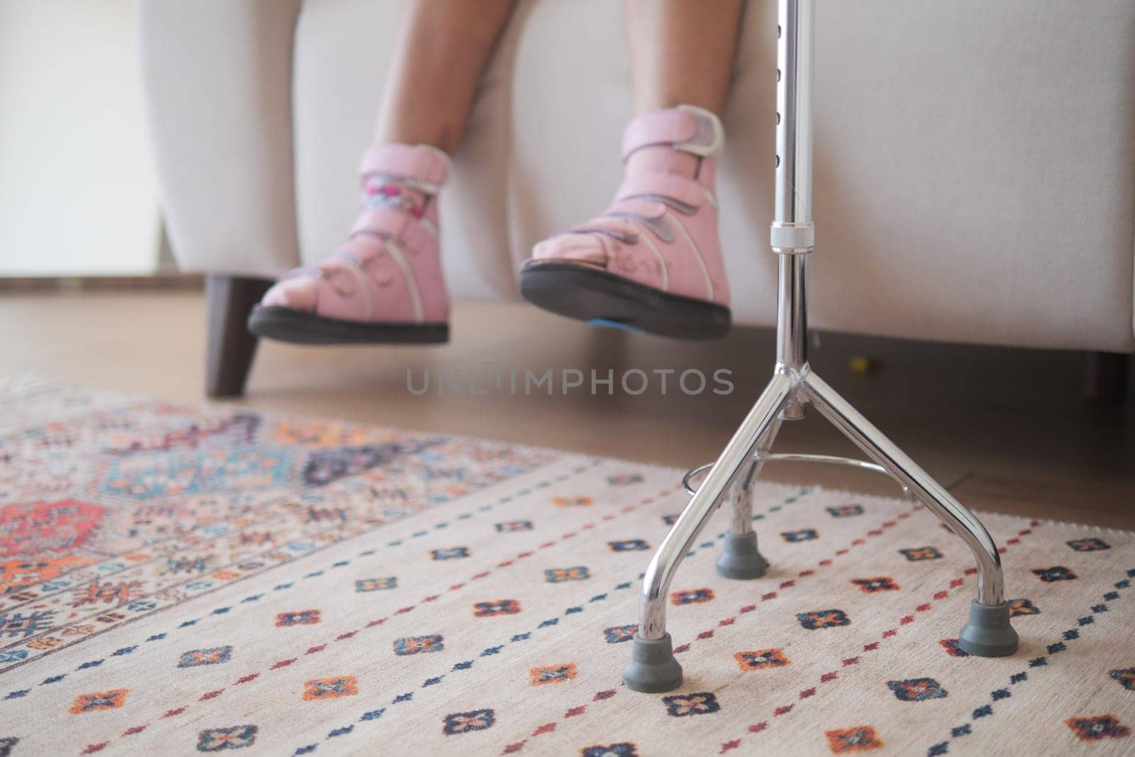 A young child relaxes on a couch, using crutches for support and comfort.