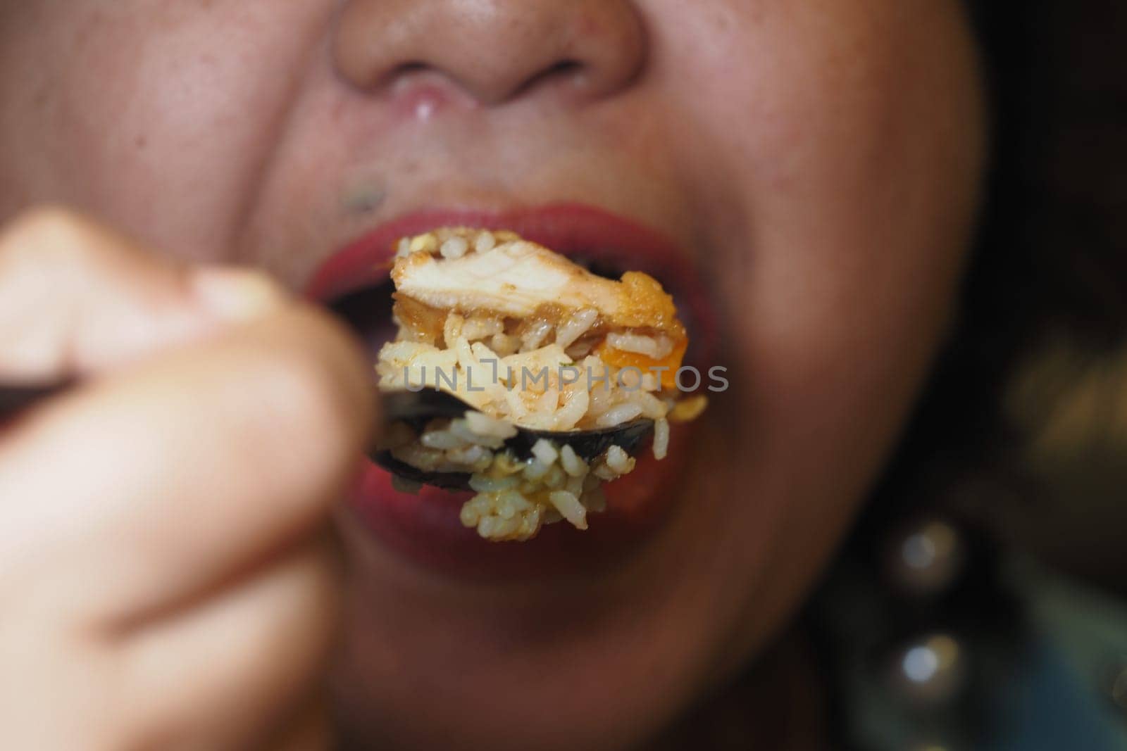 A close-up of someone savoring fried rice with chicken during dinner.