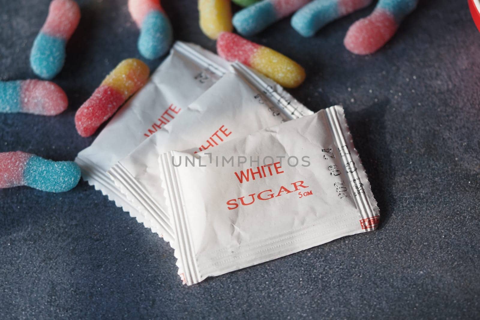 Packets of sugar are arranged with assorted gummy candies nearby.