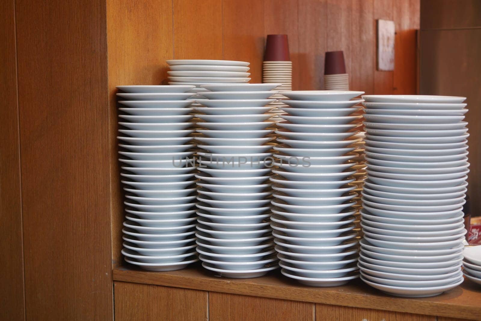 A tall stack of clean plates is organized in a restaurant setting.