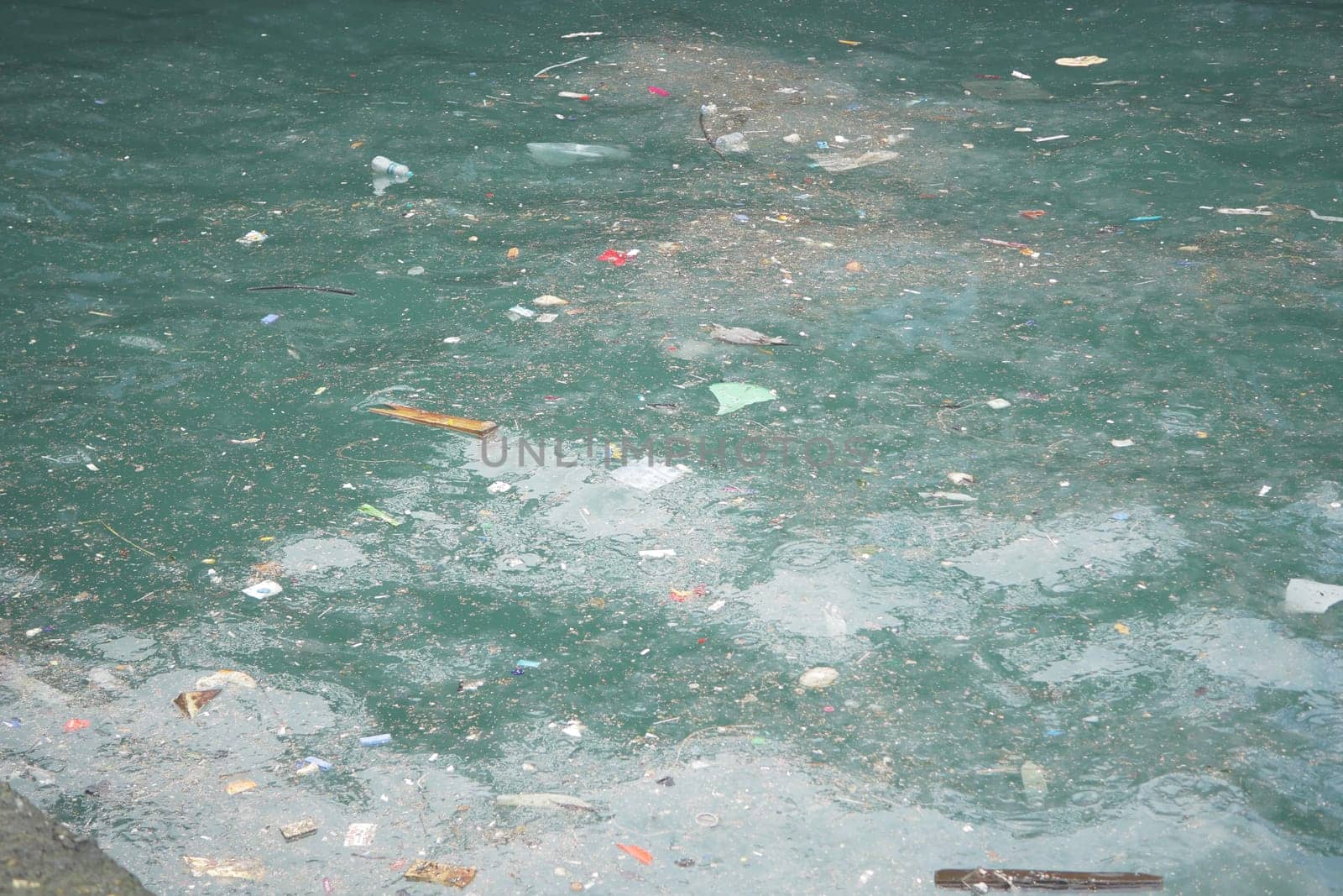 Trash and debris accumulate on the surface of water in a city.