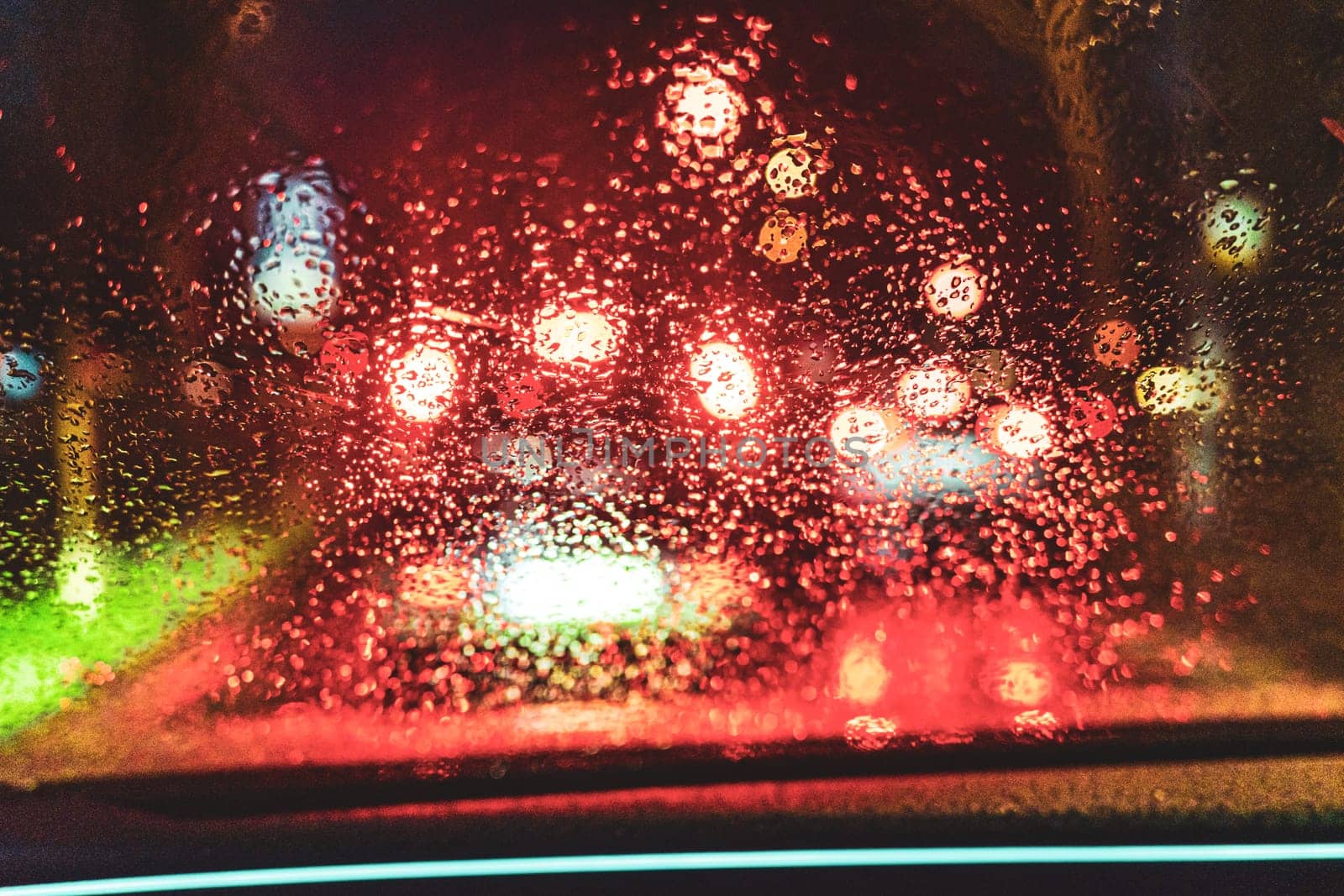 A mesmerizing view of vibrant bokeh lights seen through a rainy car window, capturing the beauty of urban nightlife and the emotional depth of isolation in transit.