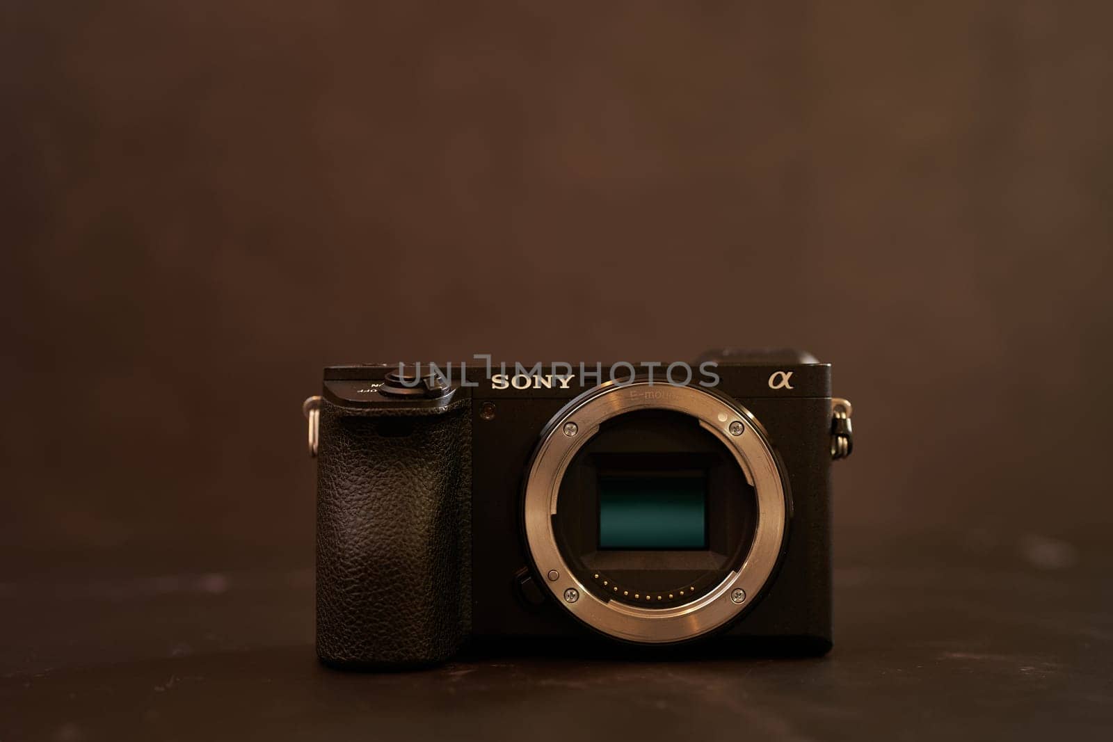 Sony A6500 mirrorless camera body stands on a black table. High quality photo