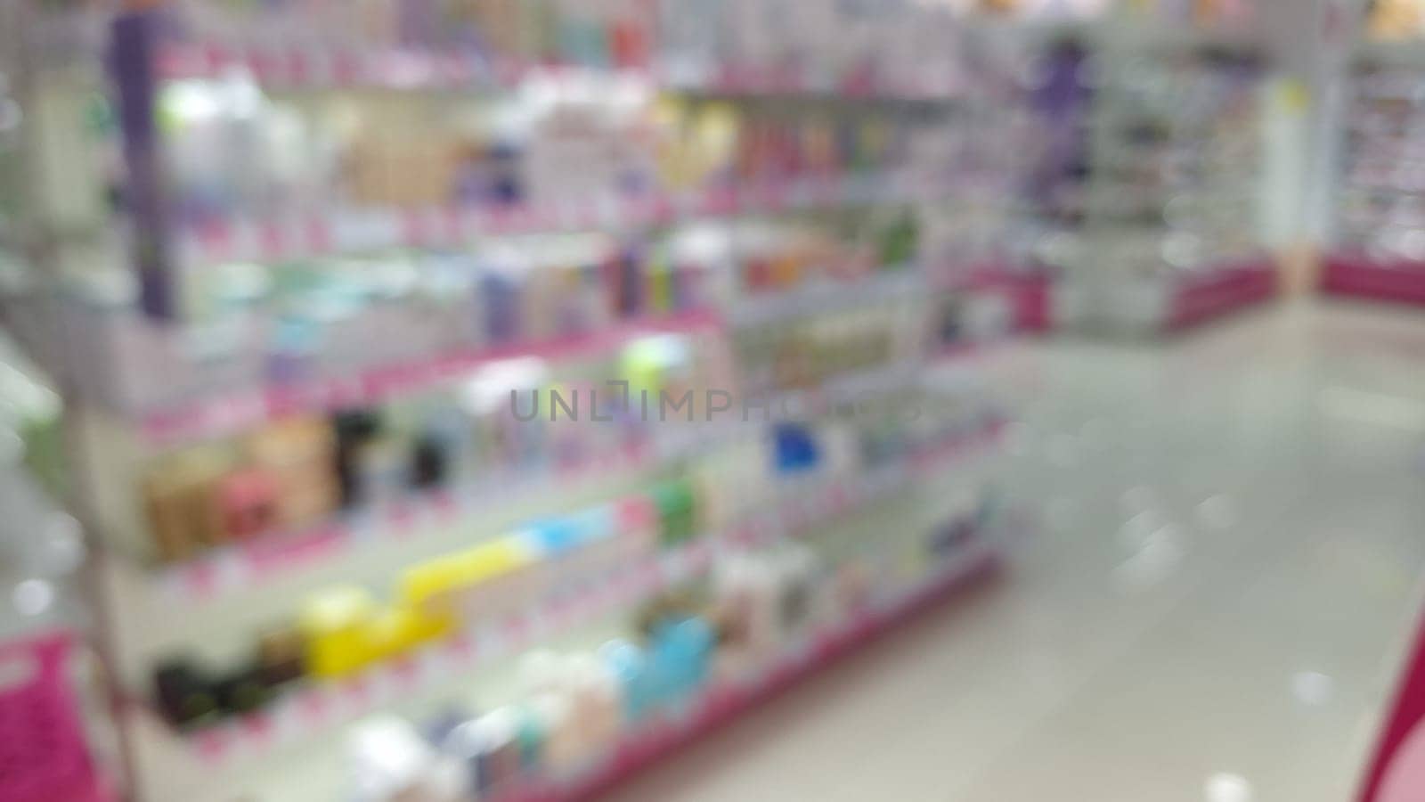 Blurred interior of a brightly lit cosmeticals store with colorful shelves.