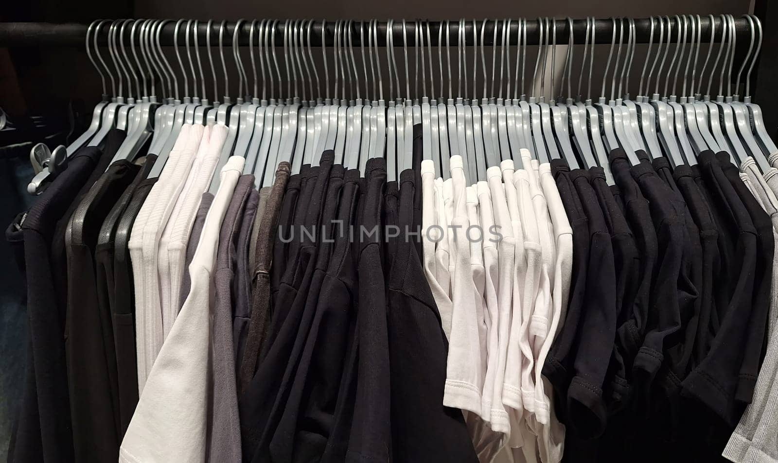 Black and white t-shirts on hangers in closet display.