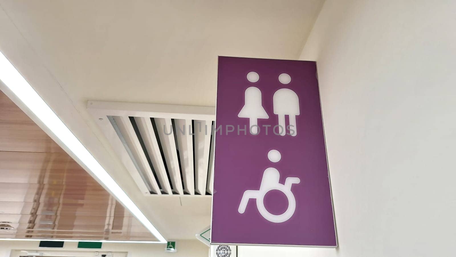 Purple accessible restroom sign with male, female, and wheelchair symbols.