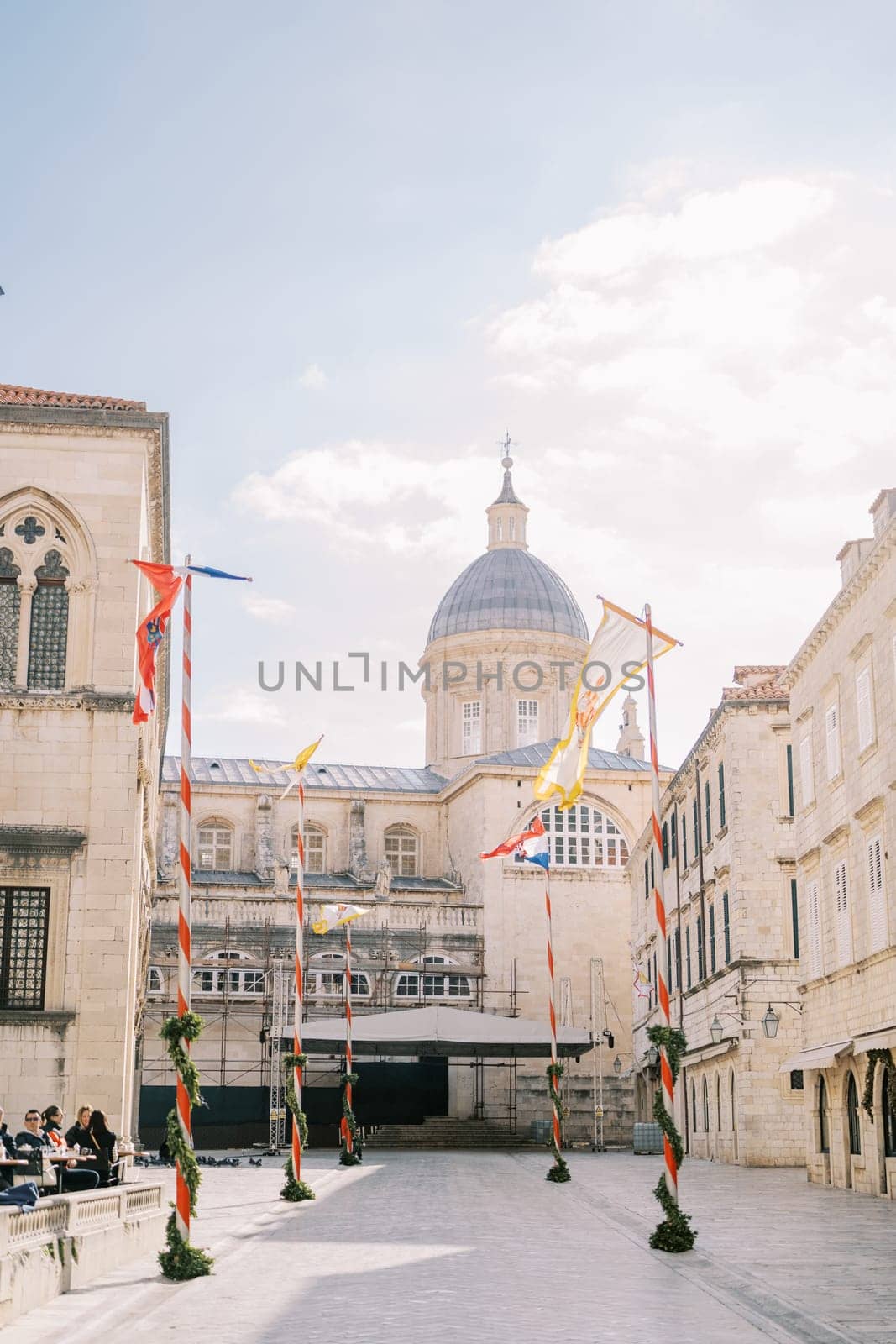 Colorful flags flutter in the wind on Stradun Square near the Cathedral of the Virgin Mary. Dubrovnik, Croatia. High quality photo
