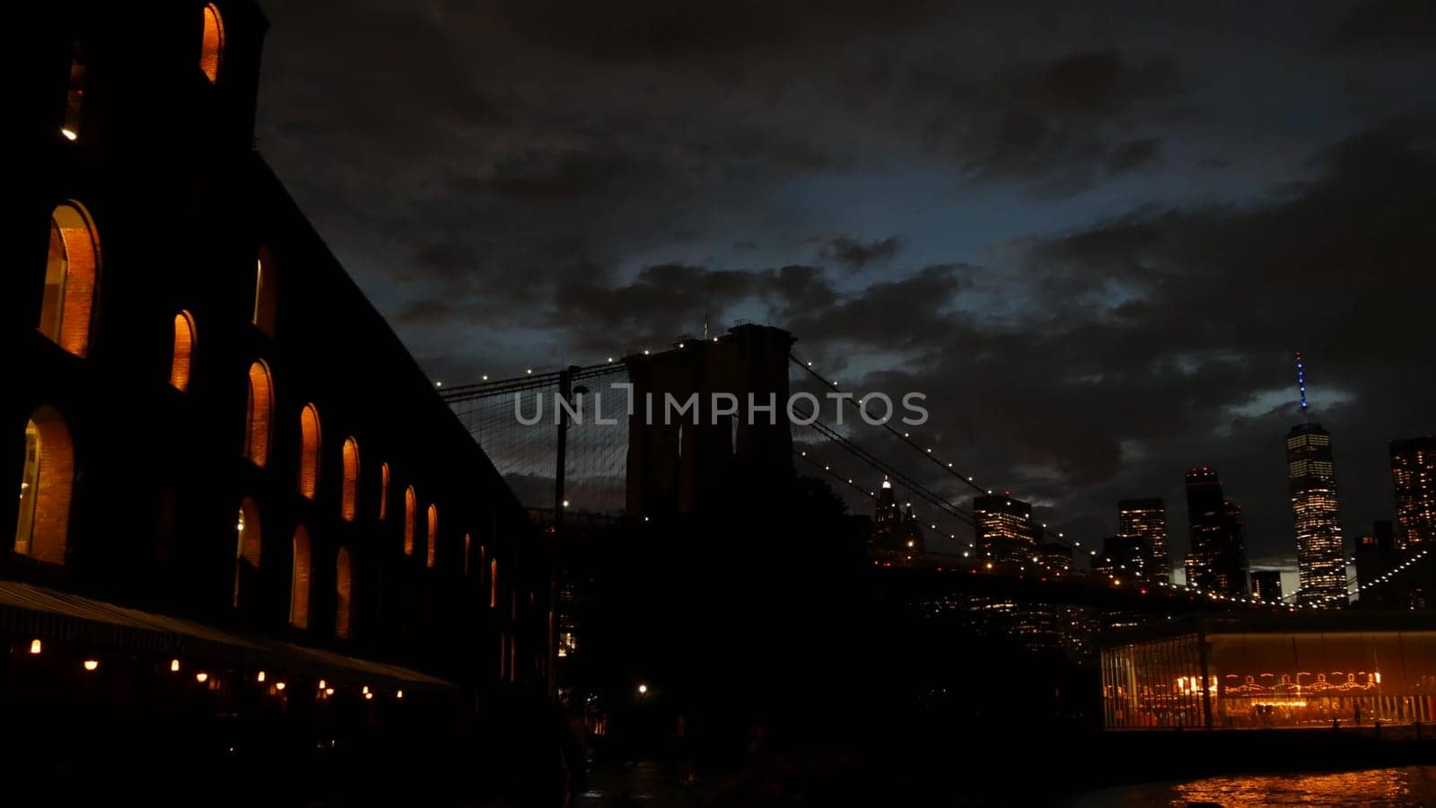 New York City, United States - 11 Sept 2023: Brooklyn Bridge, Manhattan downtown skyline cityscape. Waterfront Pebble Beach, carousel in Dumbo USA. Dramatic twilight dusk. Evening sky, Time Out Market
