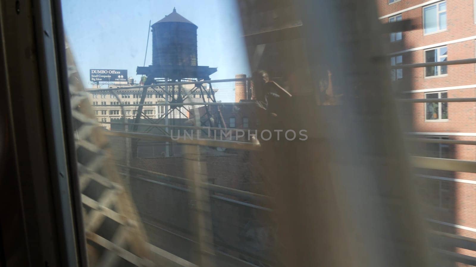 New York City, United States - 14 Sept 2023: Subway train, Manhattan bridge. Shaking camera, dirty window. Downtown metro transport metropolitan traffic. Passenger railway, water tower. Brooklyn Dumbo