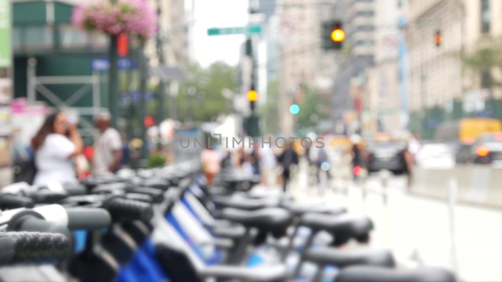 New York City Manhattan Downtown street or Midtown avenue crossroad intersection. Urban road traffic in USA. Defocused people pedestrians in United States. Blue rental bikes, sharing bicycles station.