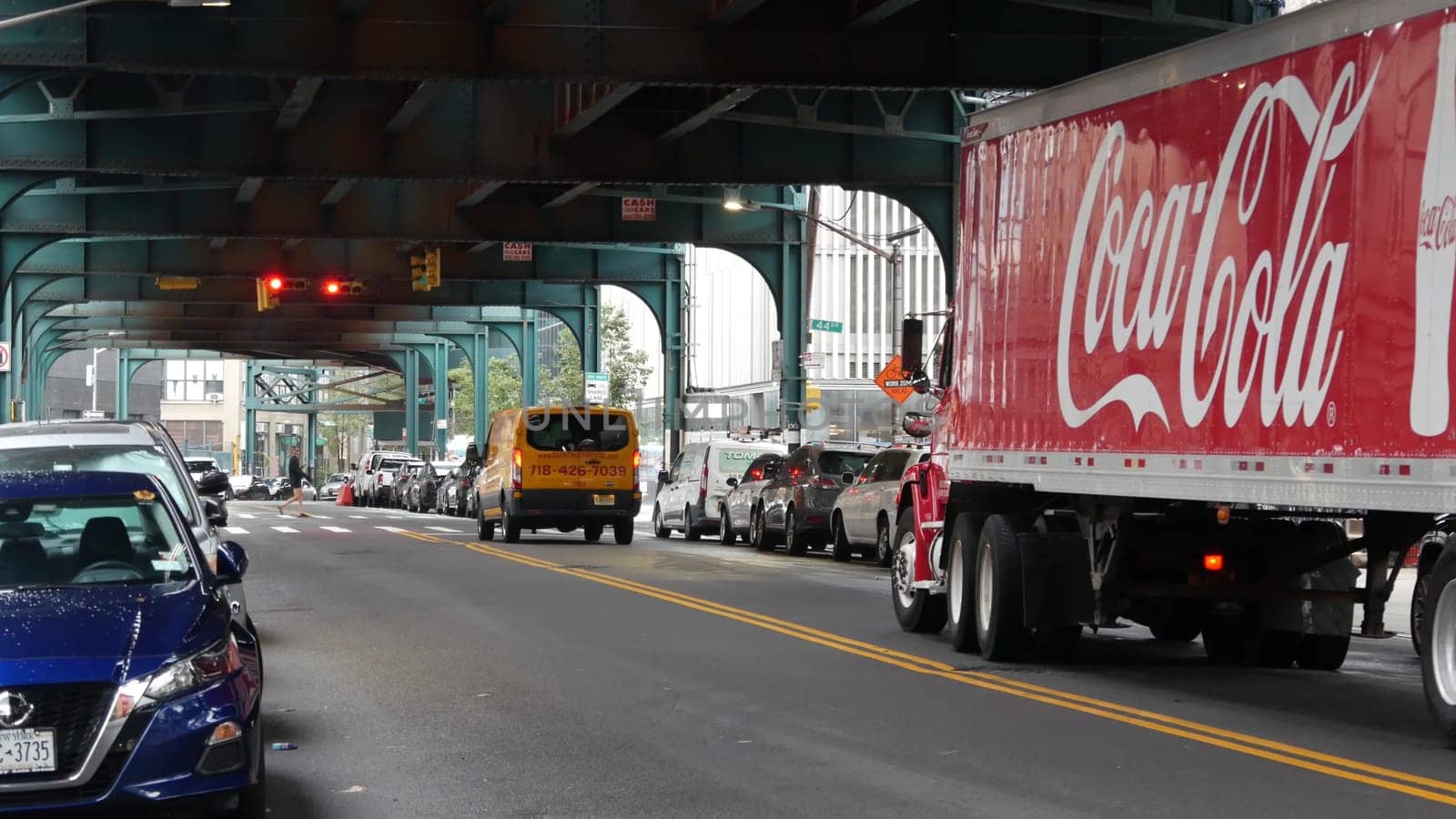 New York City, United States - 13 Sept 2023: Coca-cola truck, elevated subway above street. Metropolitan bridge over road, Queens. Long Island metro line. Coca cola delivery, Coke lorry, railway track