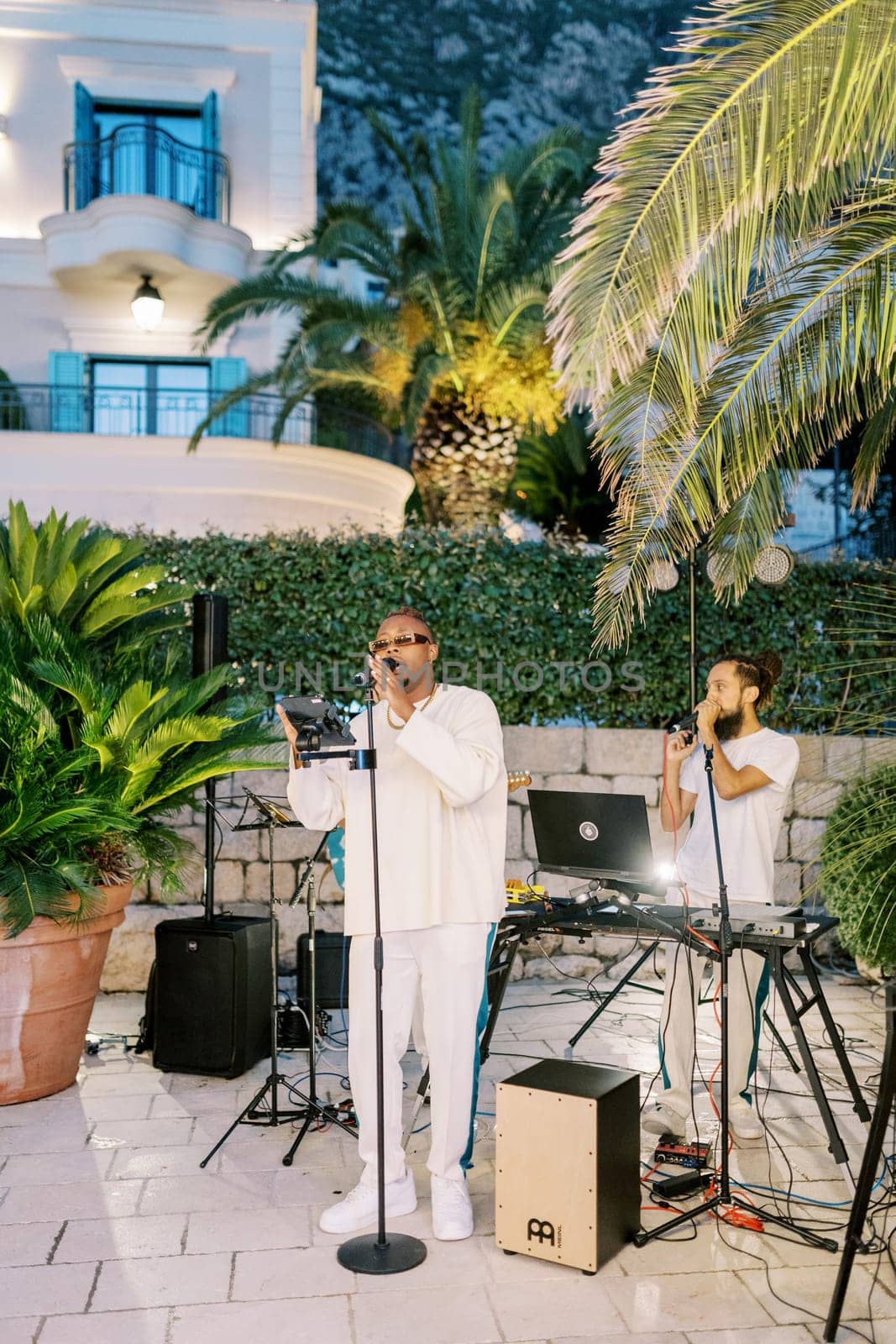 Male musical group sings on a paved area near a restaurant. High quality photo