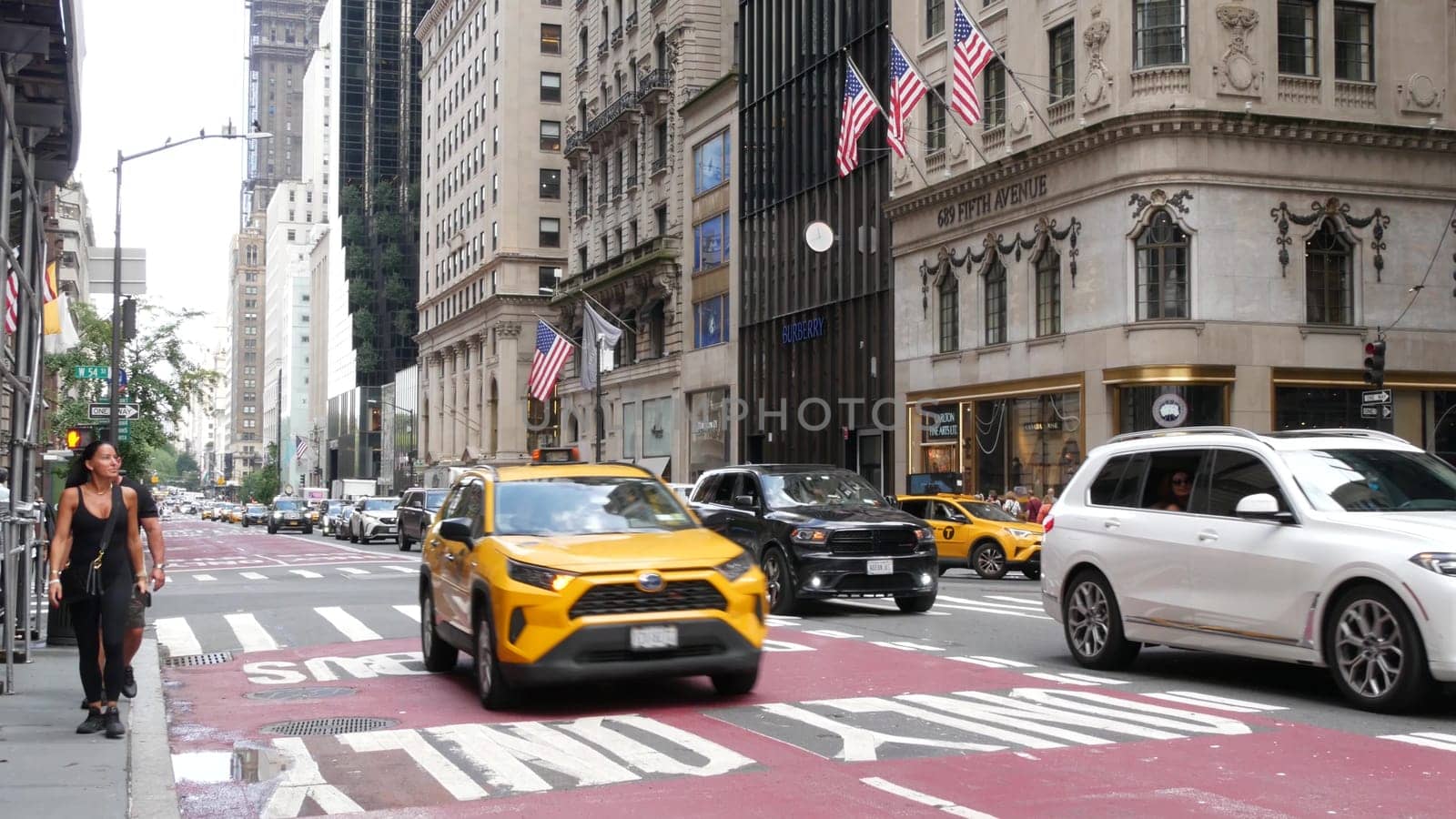 New York City, United States - 11 Sept 2023: Manhattan Midtown street, Fifth 5 avenue, 5th ave, American road car traffic, Yellow taxi cab. People pedestrians, crossroad intersection, shopping stores.