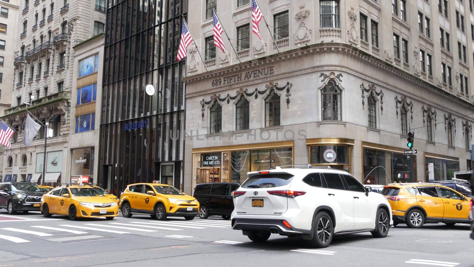 New York City, United States - 11 Sept 2023: Manhattan Midtown street, Fifth 5 avenue. American urban road car traffic, crossroad intersection. Yellow taxi cab in USA. People pedestrians go shopping.