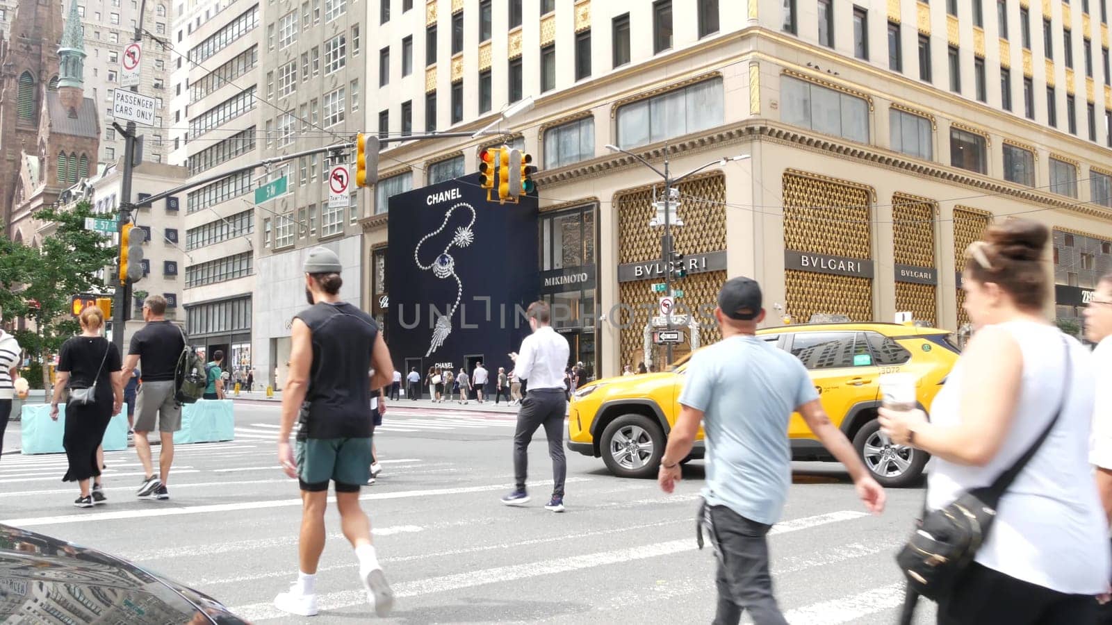 New York City, United States - 11 Sept 2023: Manhattan Midtown street, Fifth 5 avenue. Road traffic, crossroad intersection. Yellow taxi in USA. People pedestrians on zebra crosswalk. Shopping store.