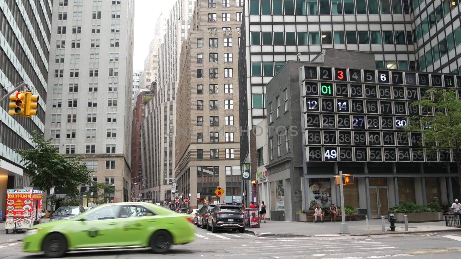 New York City, United States - 9 Sept 2023: Manhattan Downtown Financial District Water and John street crossroad intersection. USA road car traffic. Yellow taxi, people. Digital clock, bingo board.