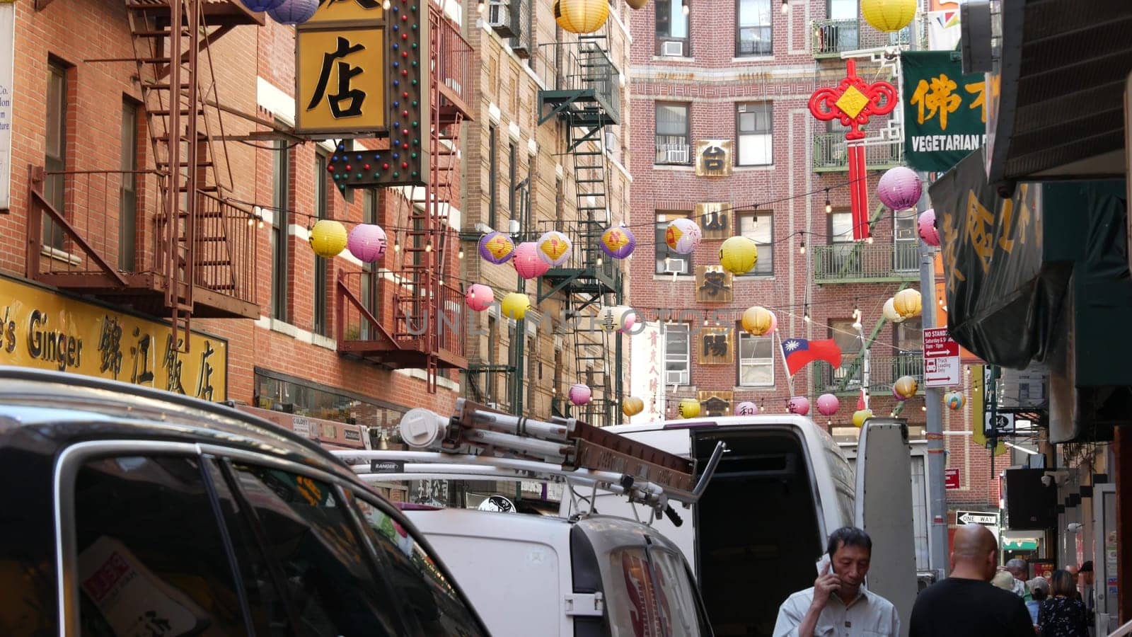 New York City, United States - 14 Sept 2023: Manhattan Chinatown Pell street. Chinese culture, ethnic district architecture, USA. Red brick buildings, round paper lanterns and hieroglyph signs. People