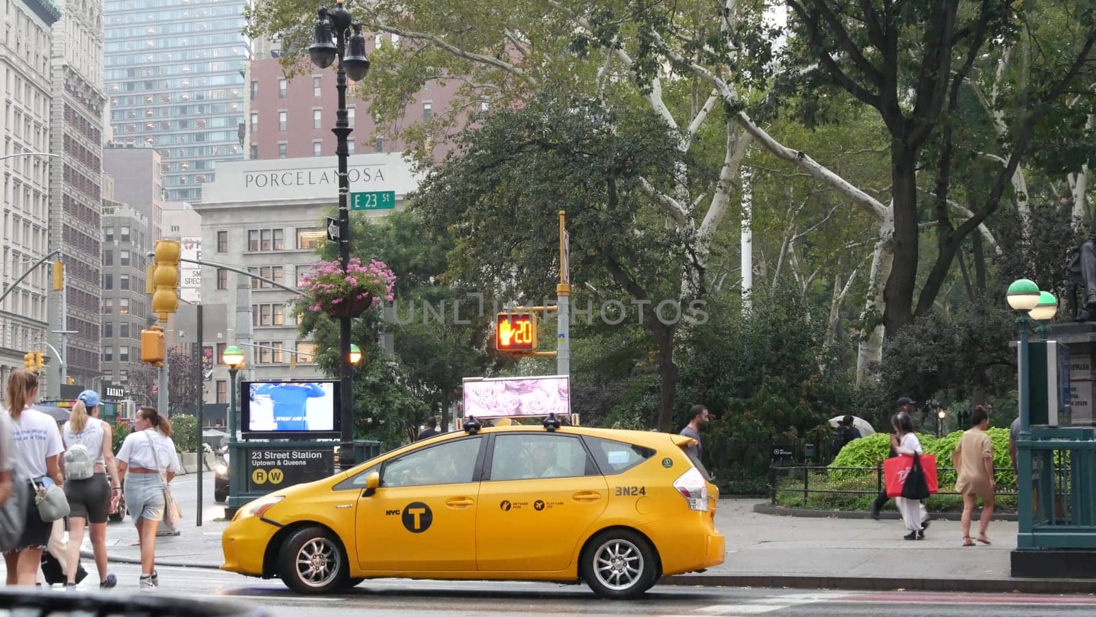 New York City, United States - 8 Sept 2023: Manhattan Midtown Broadway, 23 street, 5 avenue crossroad intersection. Madison Square Park by Flatiron Building, USA. People, subway and yellow taxi. Rain.