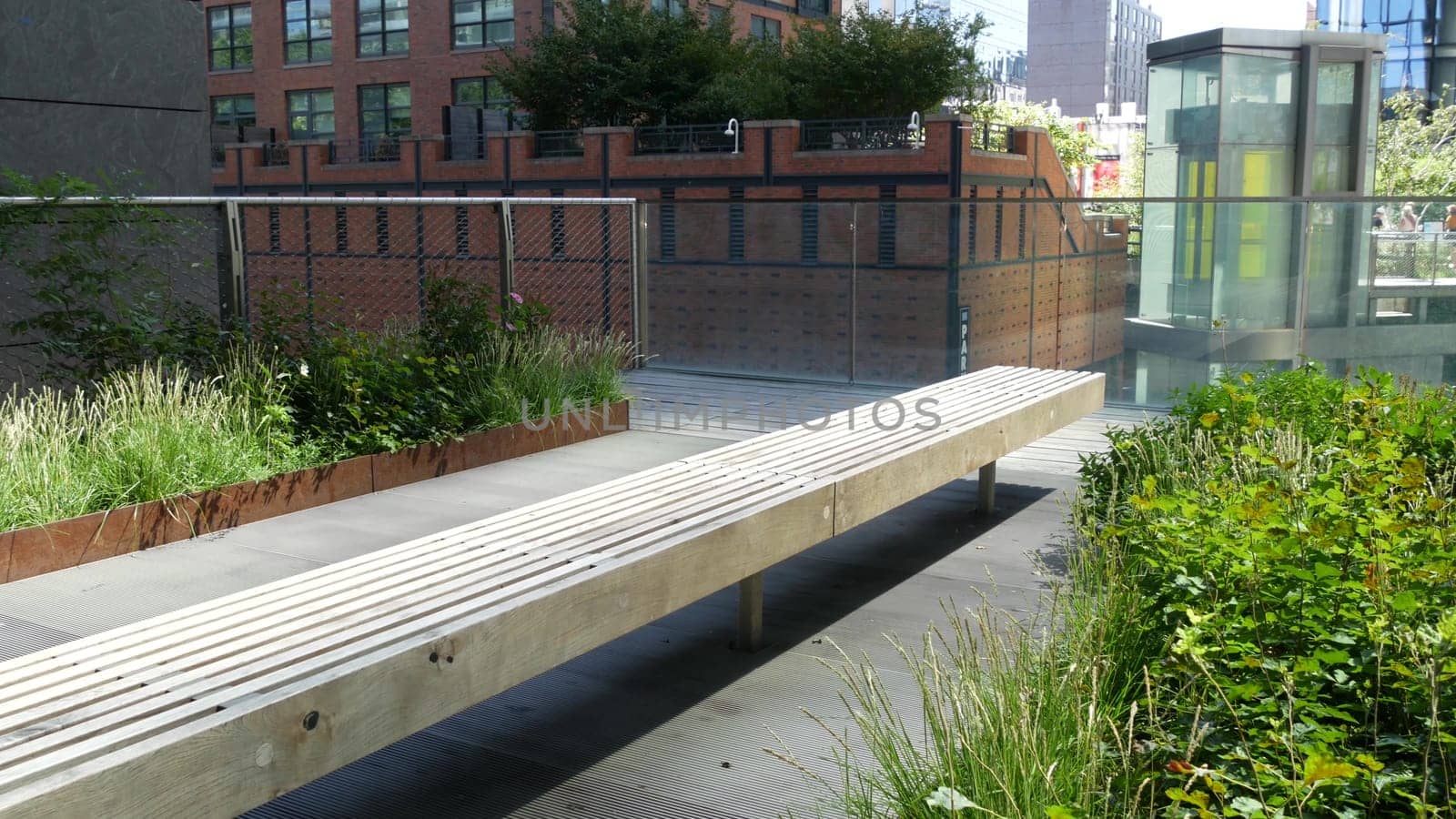 New York City, United States - 1 Sept 2023: High Line elevated greenway, Manhattan Midtown, USA. People in park. Promenade in garden greenery. American street life, Chelsea Hudson Yards. Wooden bench.