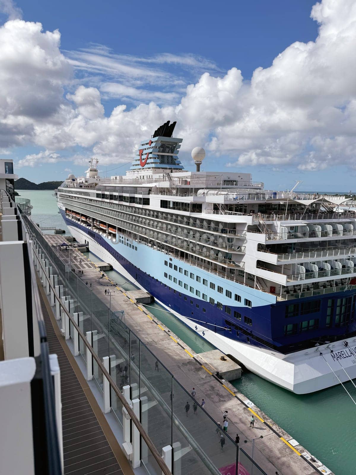 Puerto Rico, San Juan November 22. 2023 View of the Marella Discovery cruise ship docked at a tropical Caribbean pier, with turquoise waters, scattered clouds, and passengers walking along the port.