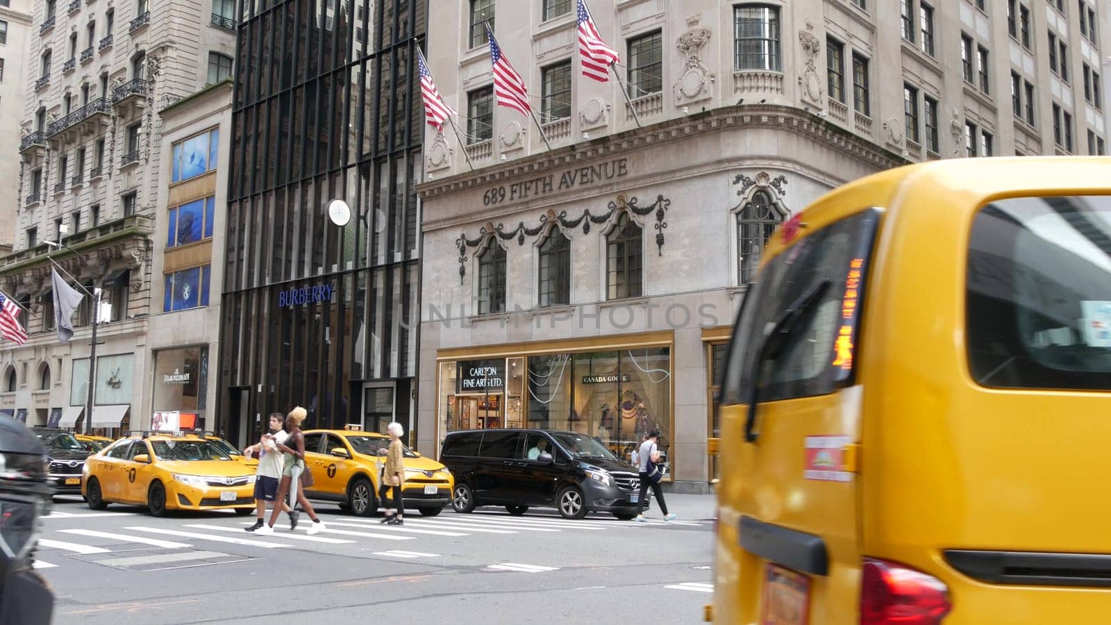 New York City, United States - 11 Sept 2023: Manhattan Midtown street, Fifth 5 avenue. American urban road car traffic, crossroad intersection. Yellow taxi cab in USA. People pedestrians go shopping.