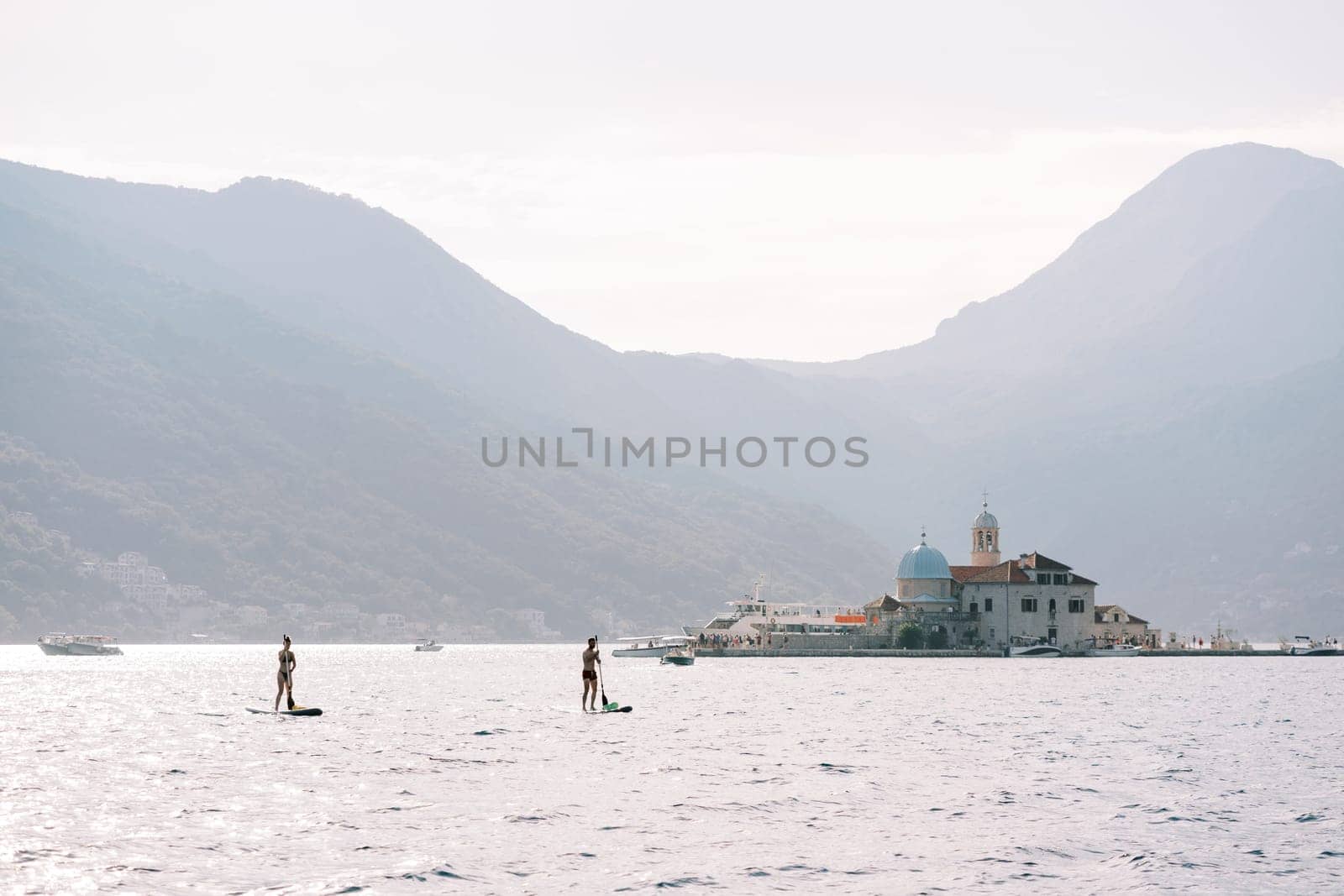 Tourists paddleboard on the sea near the island of Gospa od Skrpjela. Montenegro. High quality photo