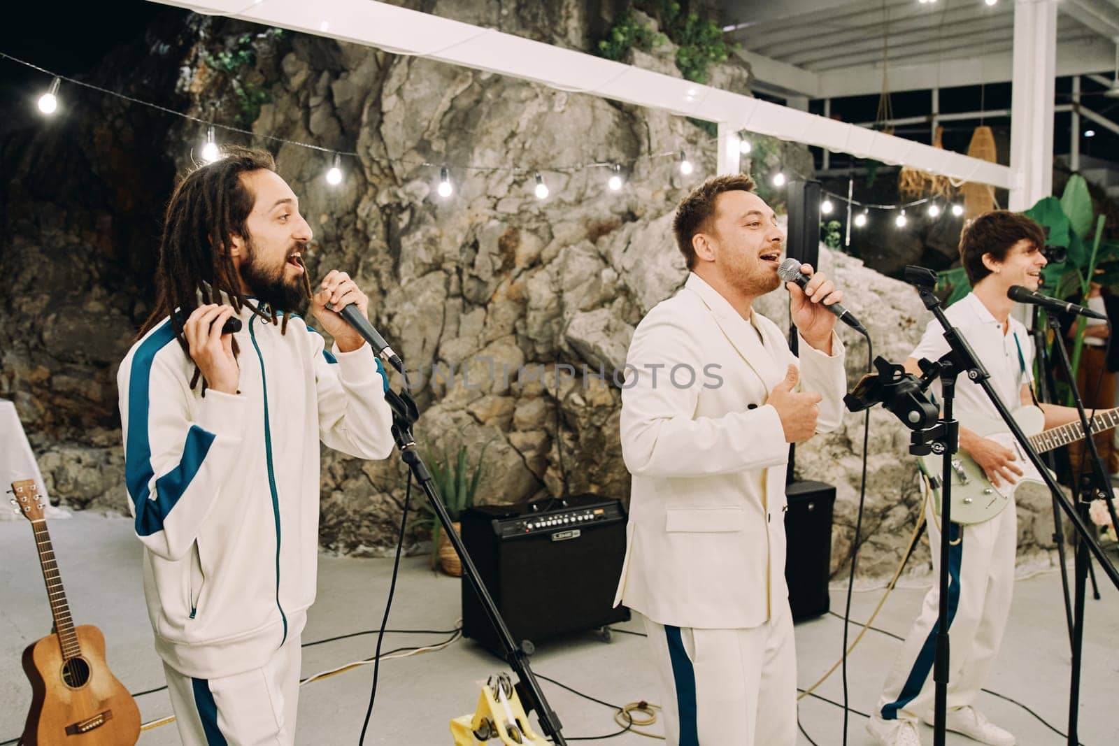 Musical group performs on a stage illuminated by garlands of light bulbs. High quality photo
