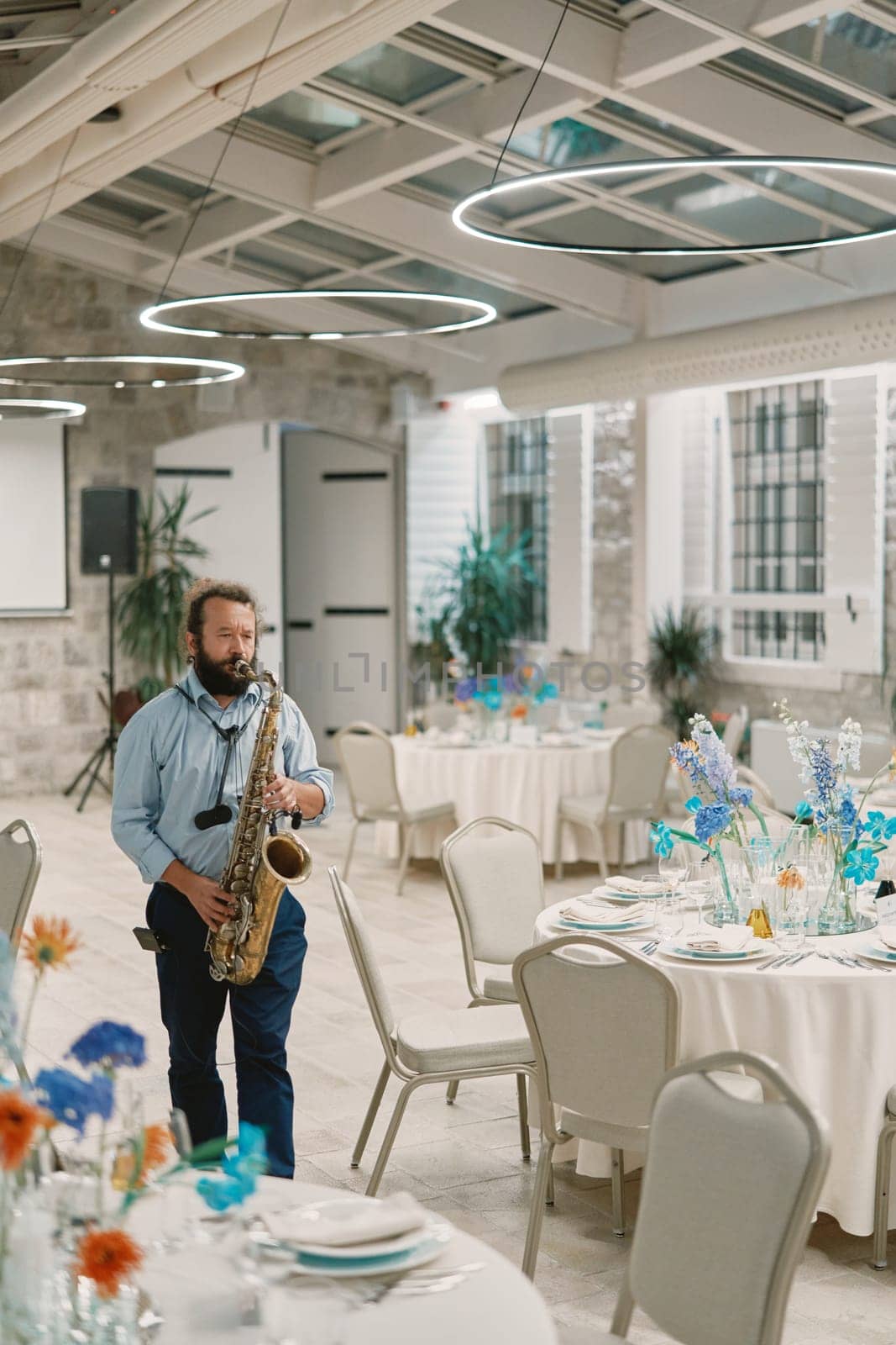 Saxophonist plays the saxophone near festive tables in a restaurant. High quality photo