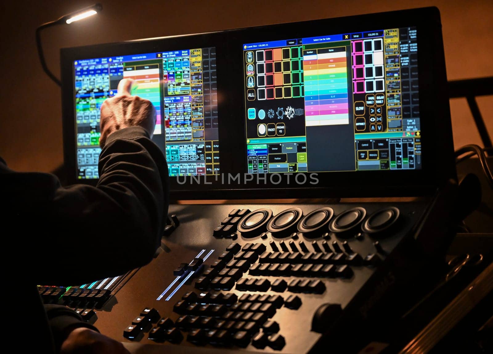A skilled technician adjusts lighting settings on a digital control board, contributing to the electrifying ambiance of a live concert at a popular venue.