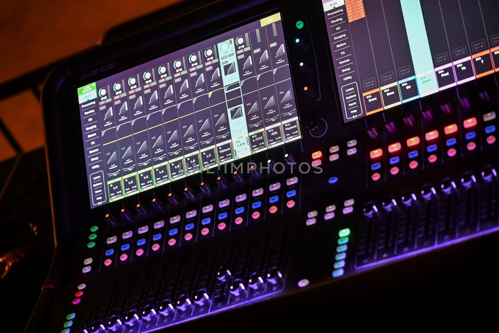 Focused sound engineer adjusts sliders and knobs on a digital mixing console while preparing for a performance in a lively venue atmosphere.