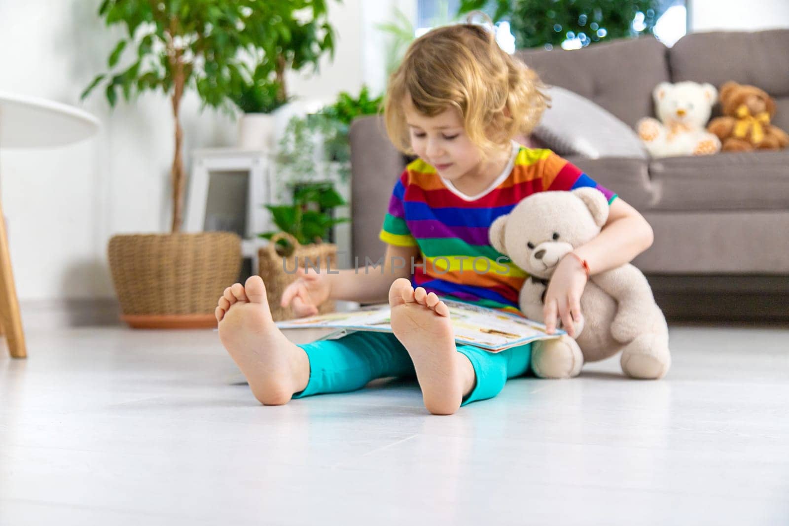 Child reading a book at home with a teddy bear at home. Selective focus. kid.