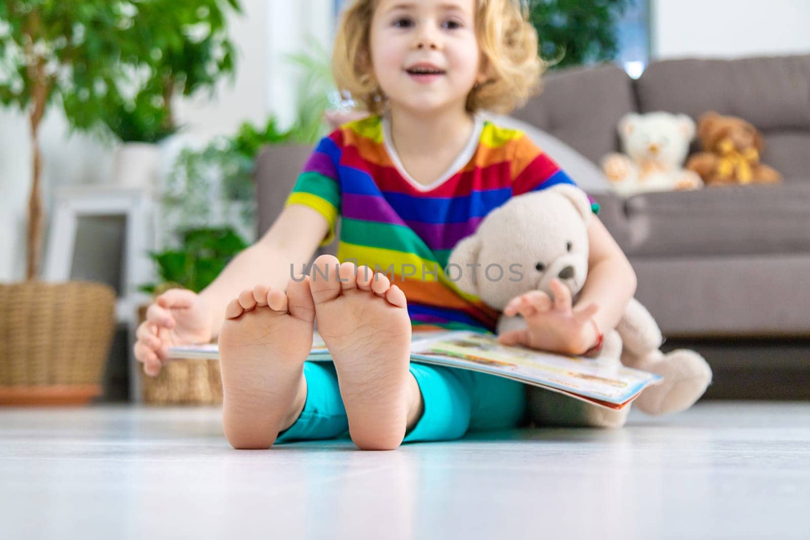 Child reading a book at home with a teddy bear at home. Selective focus. kid.